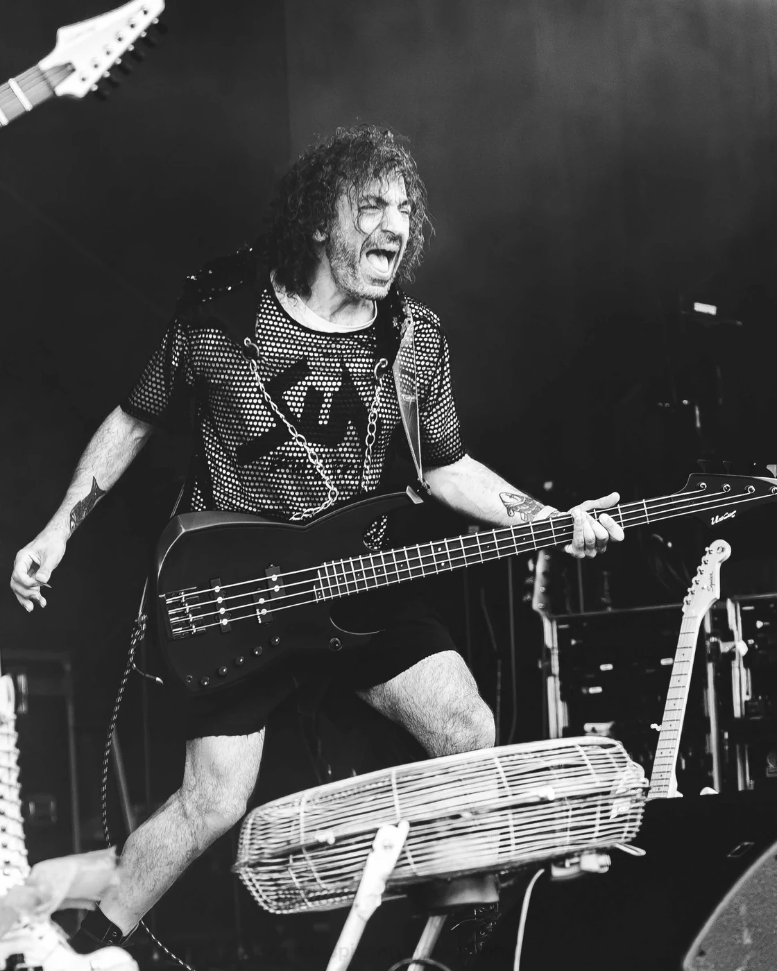 Bassiste de SUN — En noir et blanc, un bassiste aux cheveux bouclés joue la bouche grande ouverte.