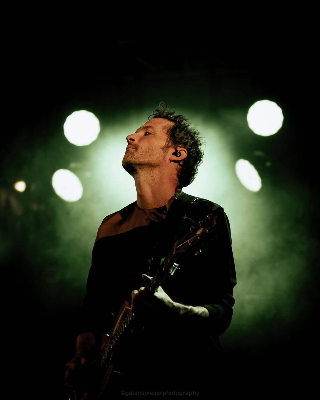 Eben — Un guitariste se détache d’un halo de lumière verte et de fumée. Musiques d’ici et d’Ailleurs · Châlons-en-Champagne · 11 juillet 2026.