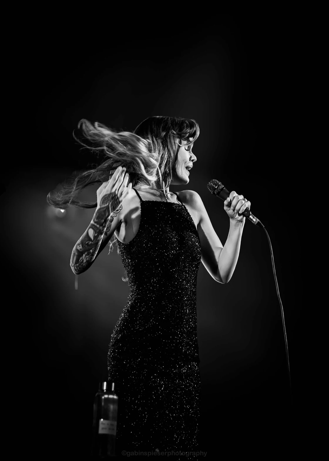Ina Forsman — En noir et blanc, une chanteuse en robe scintillante se retourne, les cheveux en mouvement.