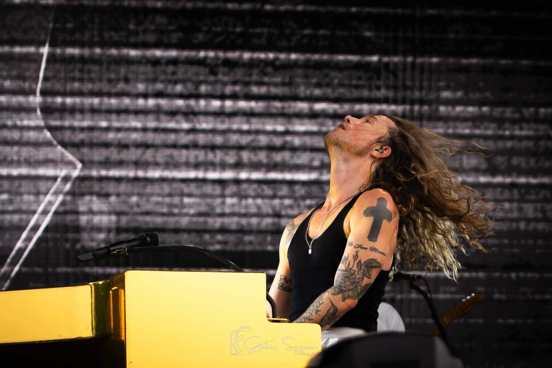 Julien Doré — Un pianiste aux cheveux en mouvement joue derrière un piano jaune.