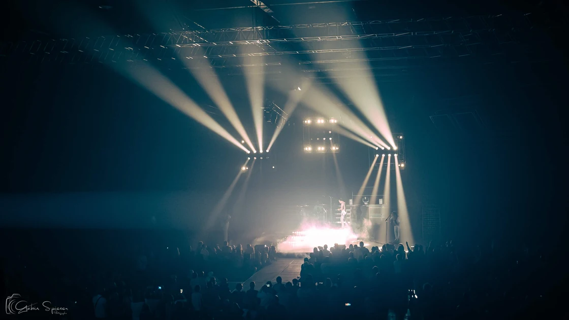 One Night of Queen — Une grande salle de concert baignée de lumière bleue, avec des faisceaux blancs au-dessus de la foule.
