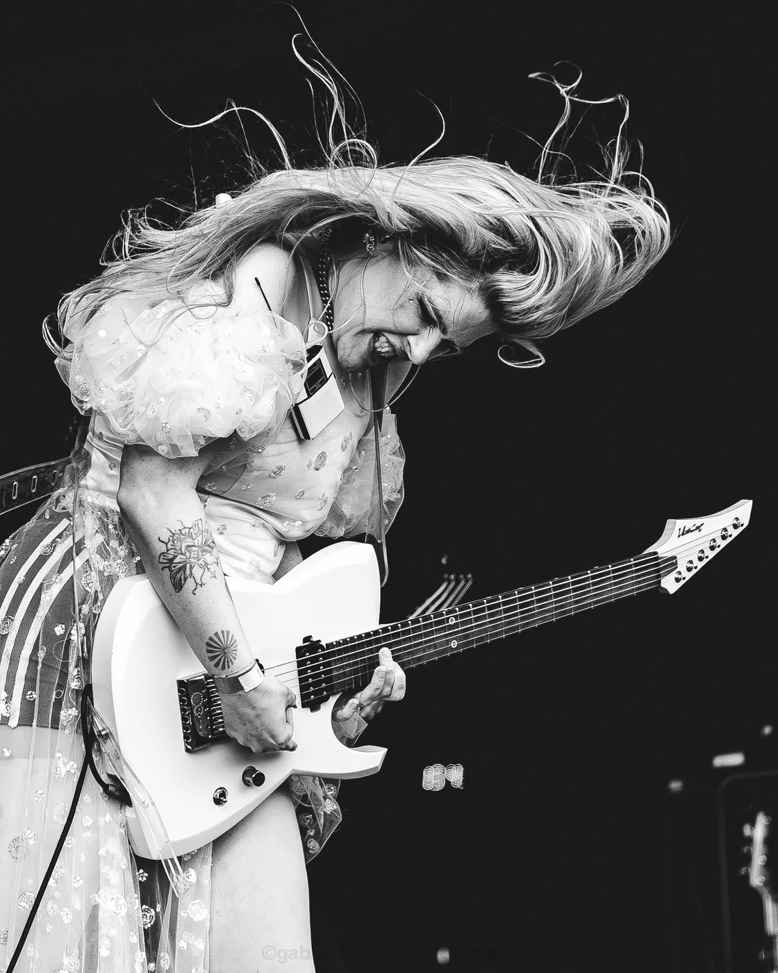 SUN · Brutal Pop — En noir et blanc, une guitariste en robe claire joue, les cheveux projetés en avant.